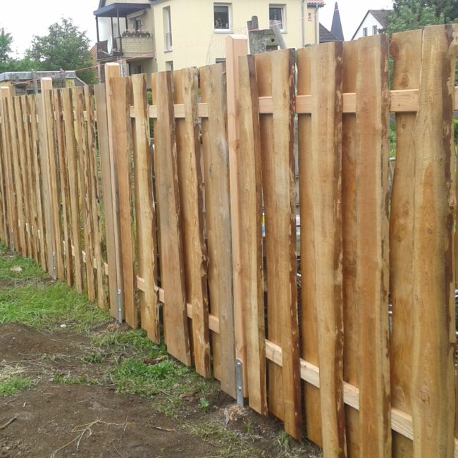 Großer Grundstückzaun, angefertigt aus Baumstammscheiben