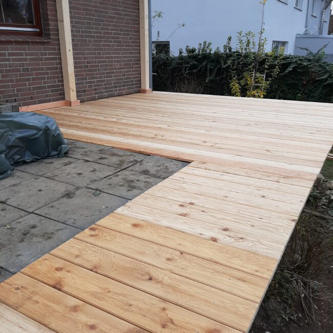 Terasse aus Holz und Stein geht um die Ecke. Bild während des Bauprozesses