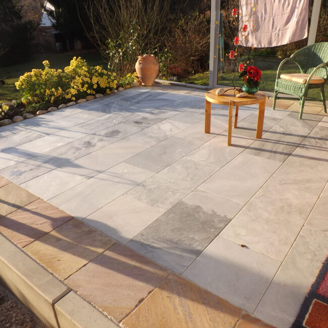 Steinterrasse aus großen Steinplatten mit Beeten und verscheidenen Steinsorten