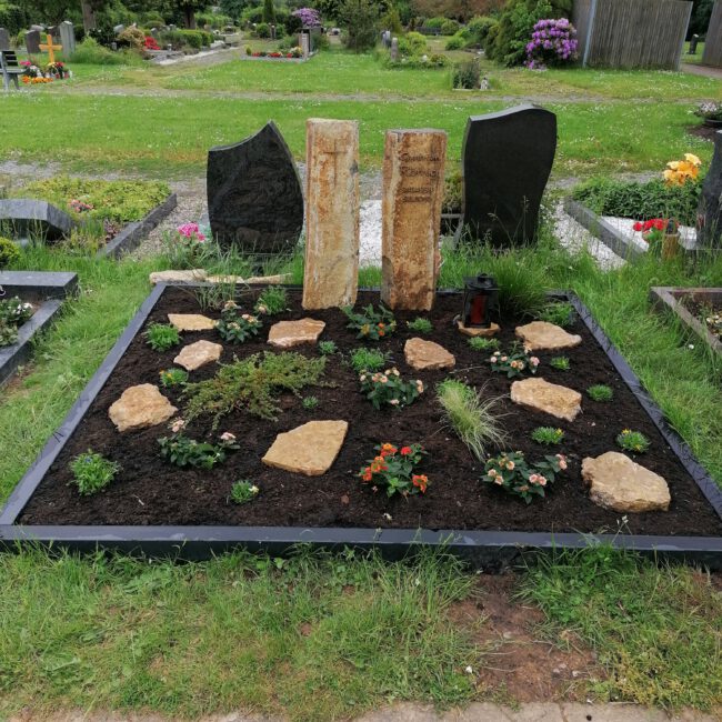Foto eines Grabes mit Sandstein und einem Beet