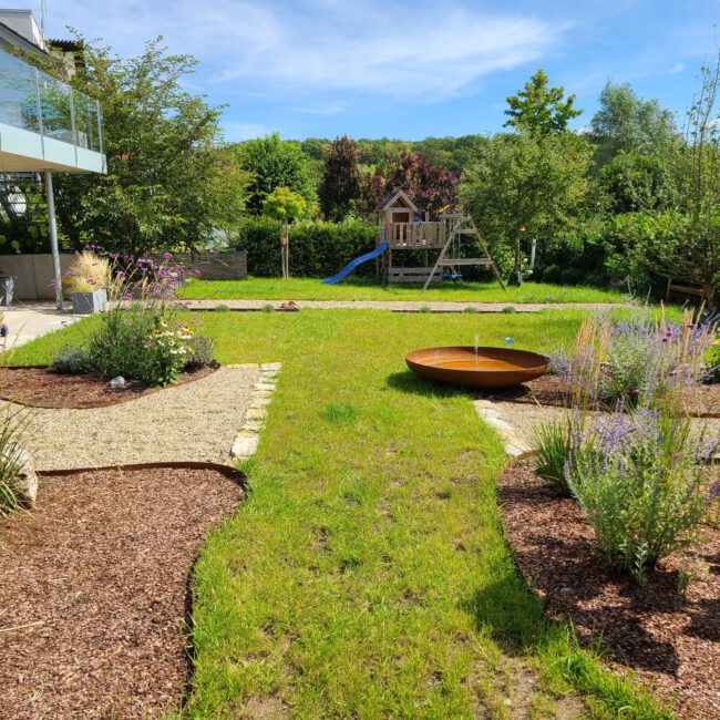 Großer weitreichender Garten mit Beeten und kleinem privatem Spielplatzbereich