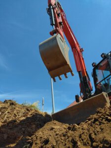 Foto von großem Bagger, der Erde beim Bau eines Gartens schaufelt